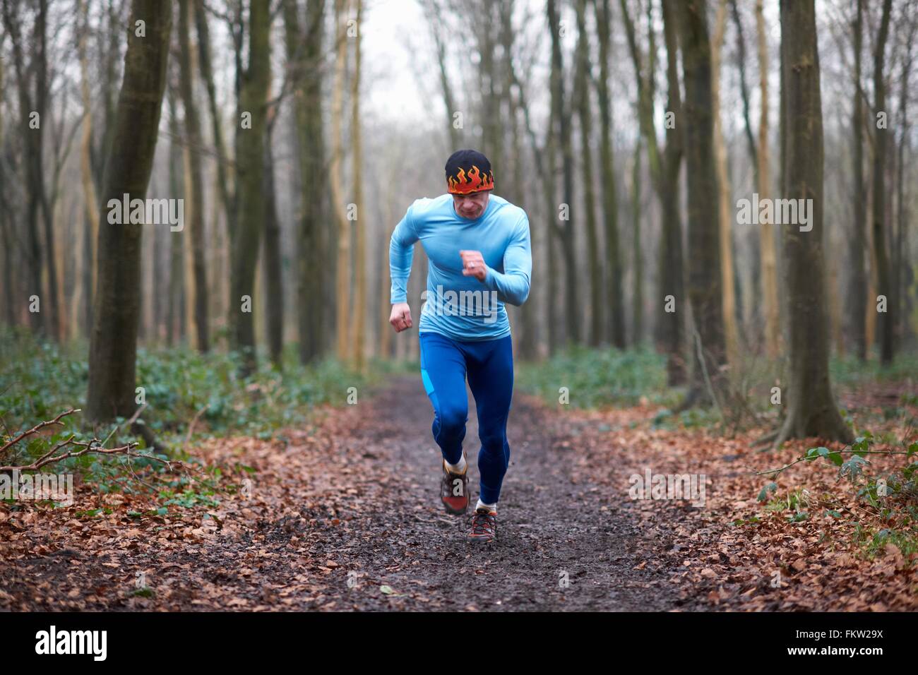 Vue avant pleine longueur de runner sur chemin bordé d'arbres à la bas Banque D'Images