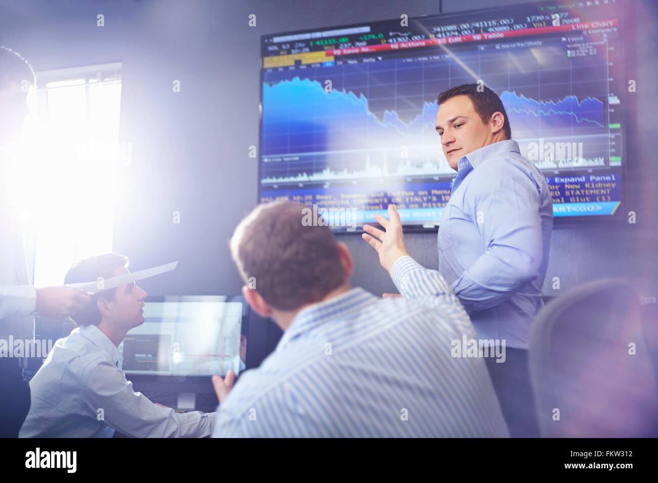 Collègues de bureau pointant sur l'écran graphique mural having discussion Banque D'Images