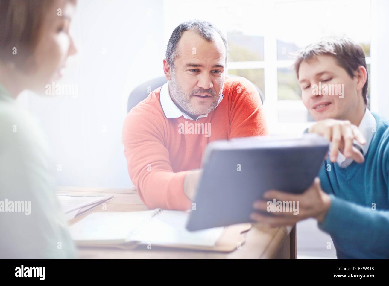 Mid adult man in office montrant collègues digital tablet Banque D'Images