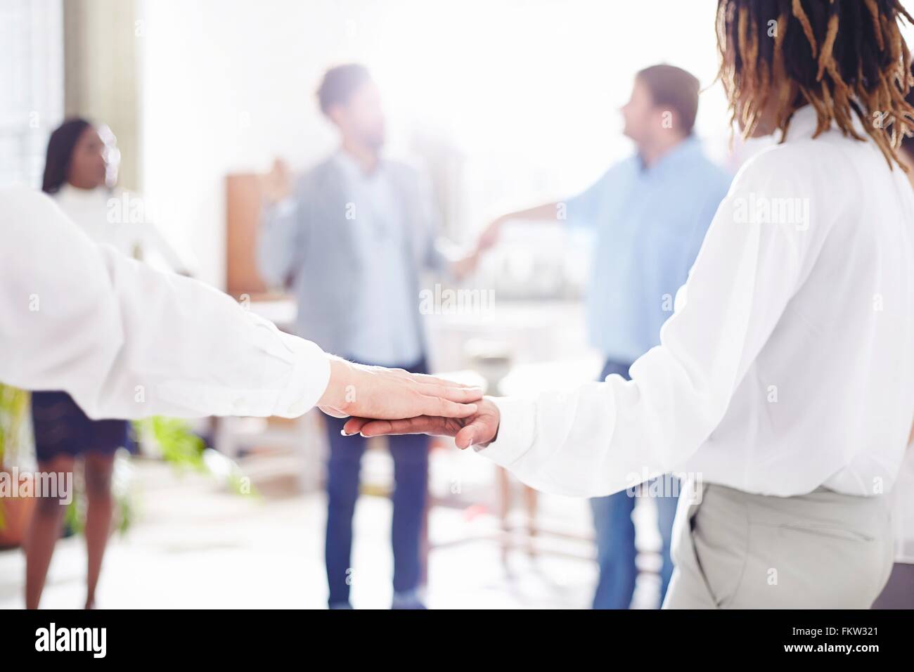 Collègues de travail team building standing in circle holding hands Banque D'Images