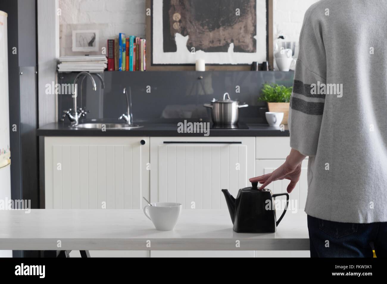 Vue arrière de la femme en attente d'un plateau de brasser sur table de cuisine Banque D'Images