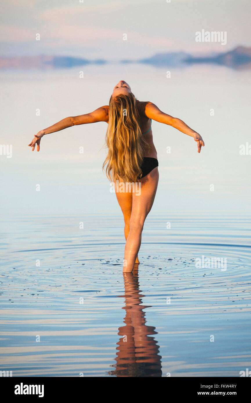 Vue arrière de danseuse en équilibre avec de longs cheveux blonds dans le lac, Bonneville Salt Flats, Utah, USA Banque D'Images