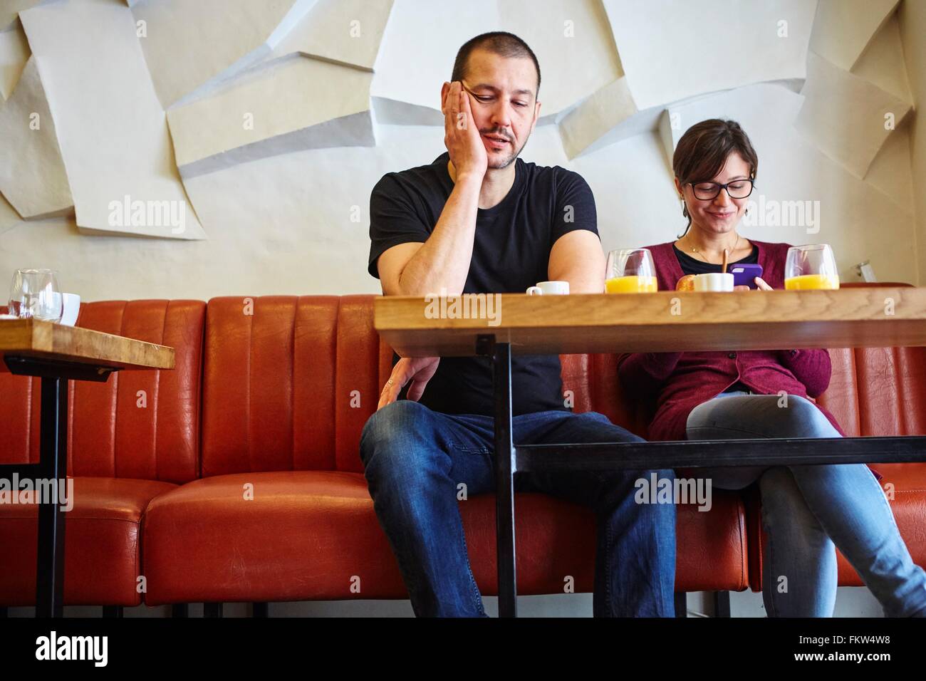 Bored man avec lecture du texte en petite amie smartphone restaurant Banque D'Images