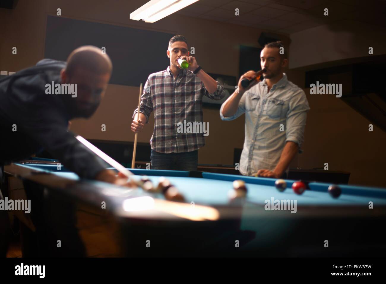 L'homme jouant au billard, les amis de boire une bière en arrière-plan Banque D'Images