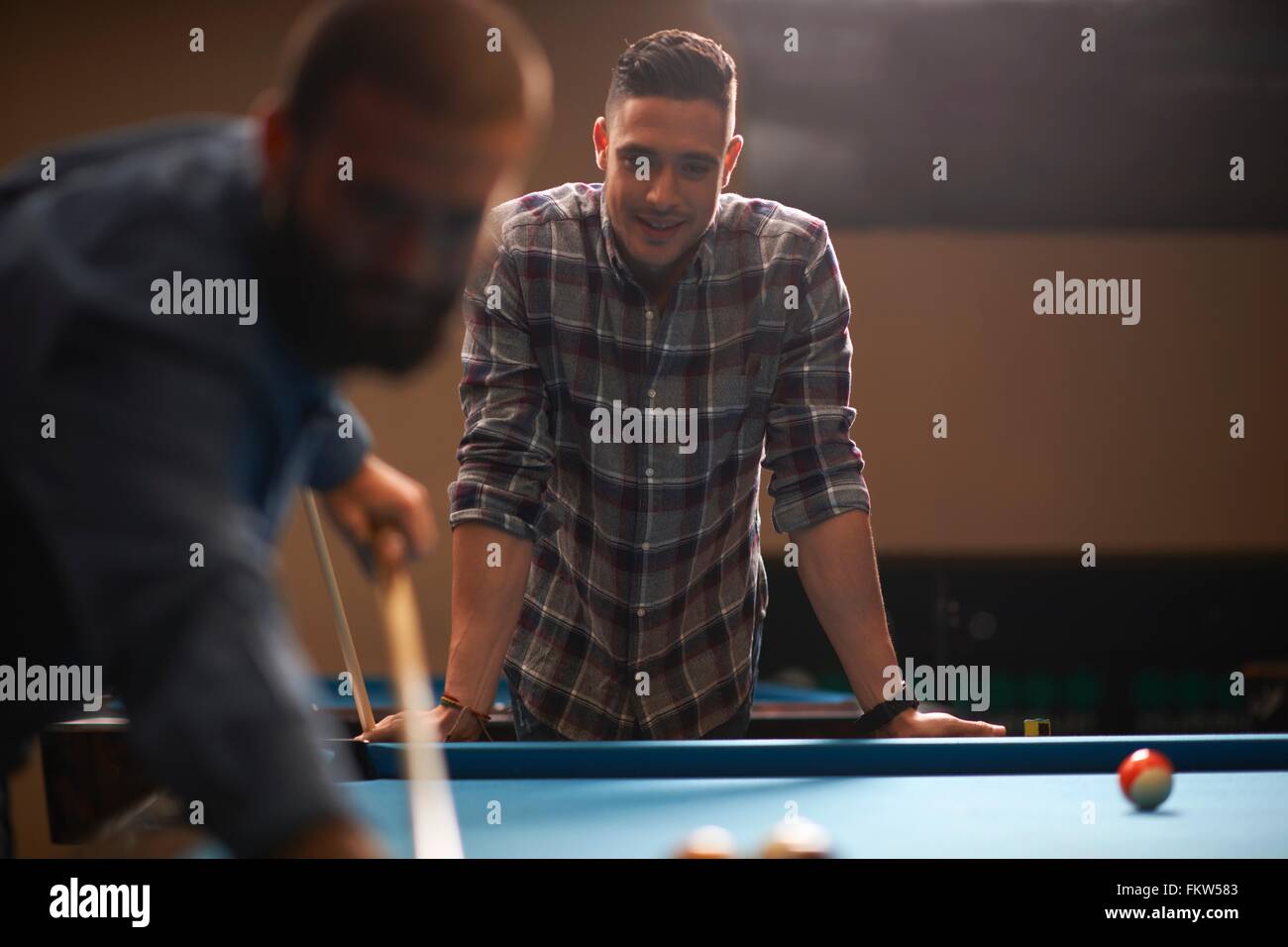 L'homme jouant au billard, ami en arrière-plan Banque D'Images