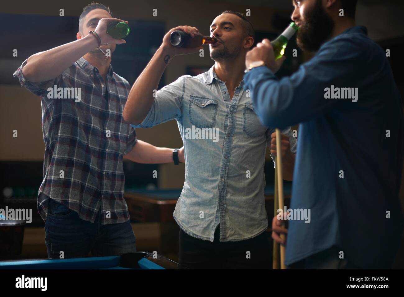 Les hommes de boire une bière au pool club Banque D'Images