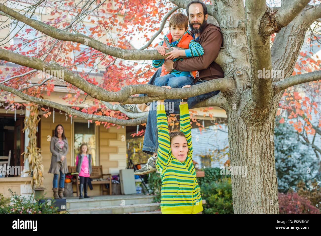 Le père et les enfants climbing tree in garden Banque D'Images