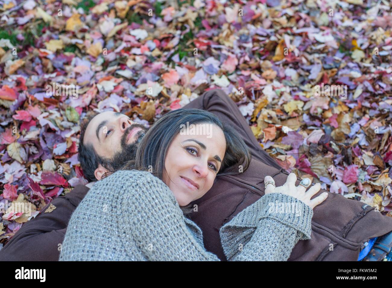 Couple lying on autumn leaves in garden Banque D'Images