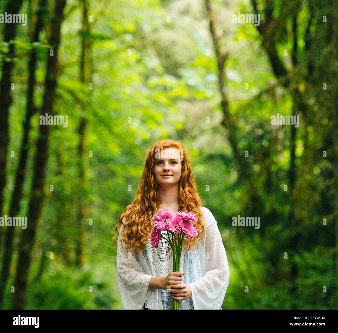 Young woman holding bouquet de gerberas rose en forêt Banque D'Images