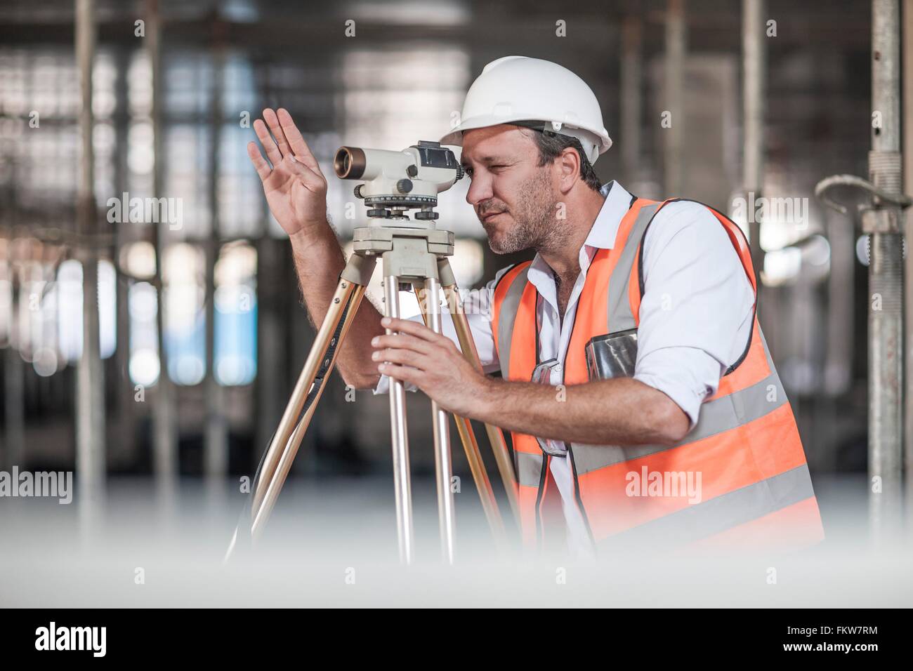 Surveyor théodolite mâle regardant à travers on construction site Banque D'Images