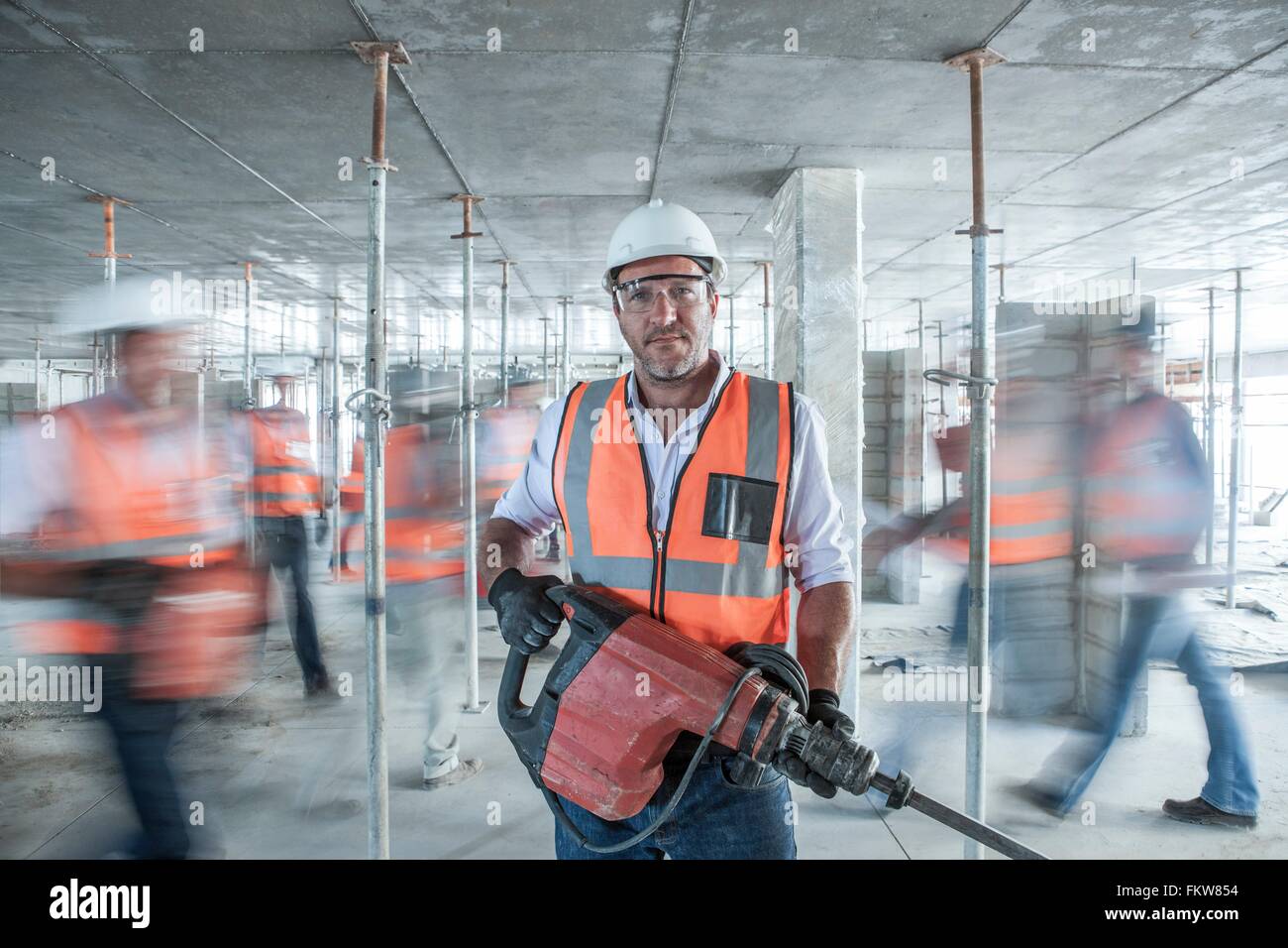 Mid adult male builder holding building construction site occupé sur l'équipement Banque D'Images