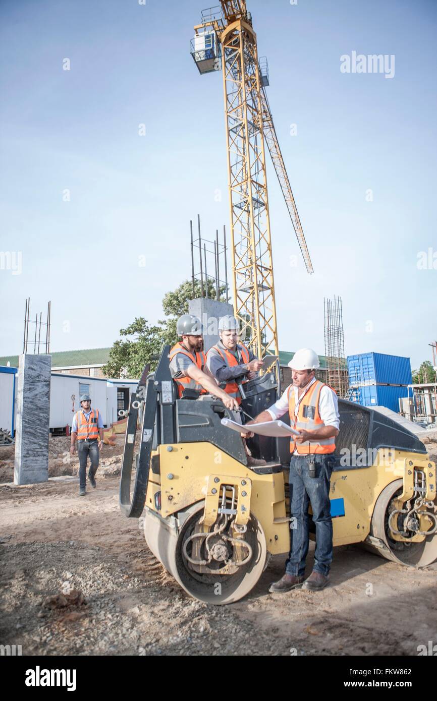 Gestionnaire du site parler avec les conducteurs sur blueprint on construction site Banque D'Images