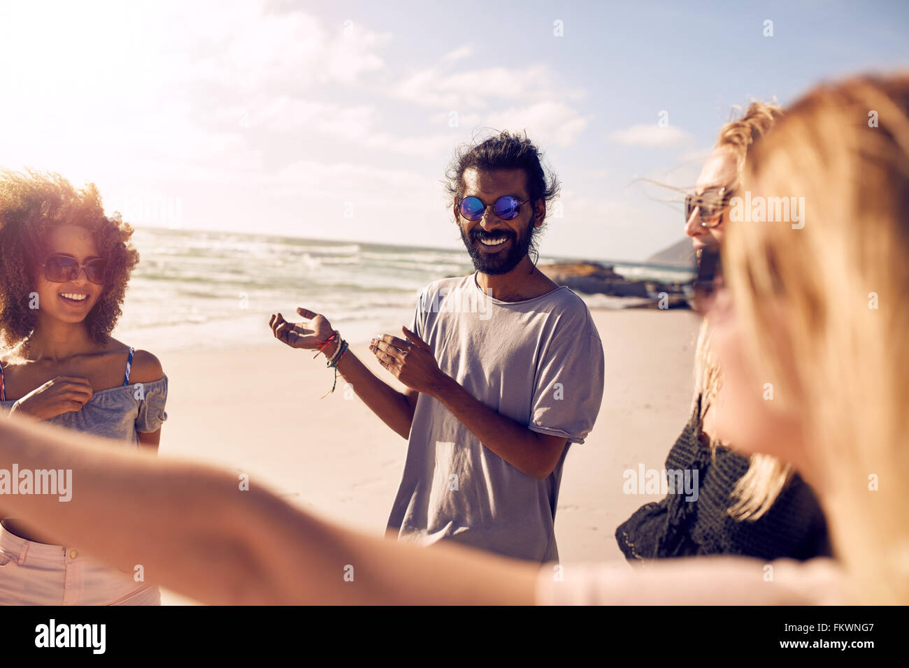 Groupe varié de jeunes se tenant ensemble et parler. Les amis s'amuser sur une journée ensoleillée à la plage. Banque D'Images