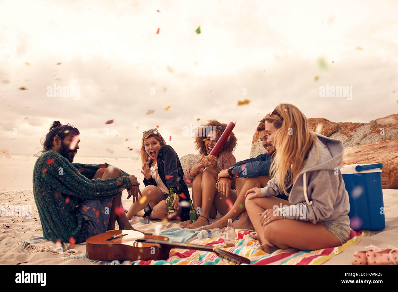 Heureux les amis à faire la fête sur la plage avec des boissons et des confettis. Heureux les jeunes de s'amuser à la plage), de célébrer avec con Banque D'Images