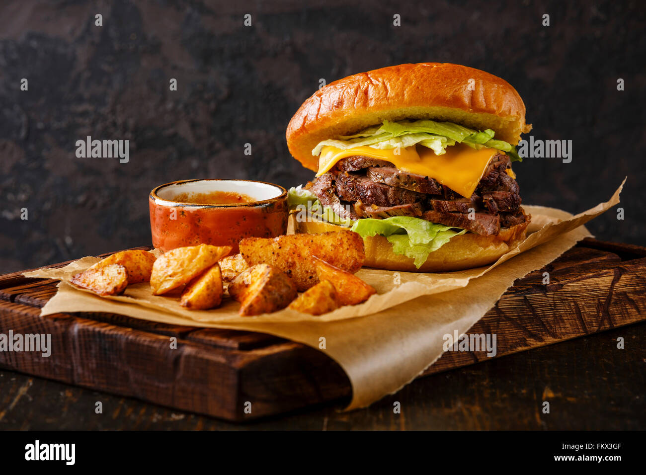 Pastrami Burger avec des tranches de rôti de bœuf et les quartiers de pommes de terre sur fond sombre Banque D'Images