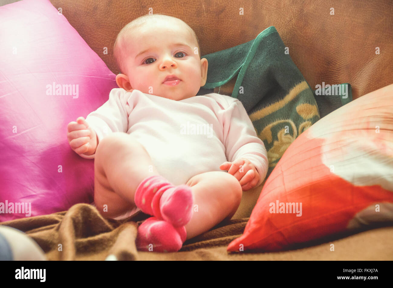 Vintage enfant nouveau-né parmi les oreillers coussins colorés Banque D'Images