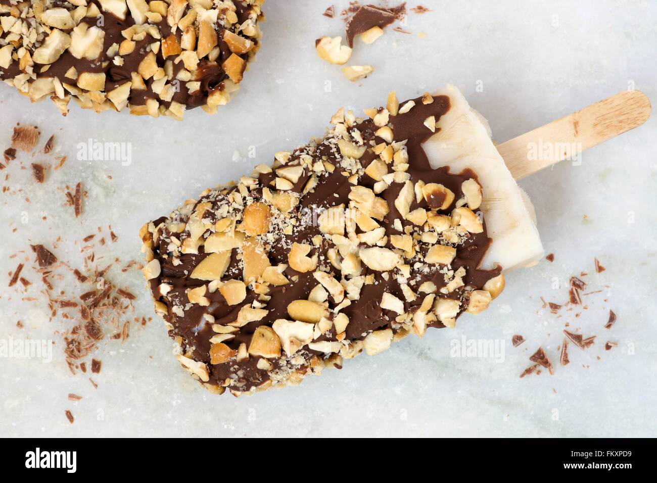 Sucettes glacées au chocolat fait maison avec des écrous. Vue aérienne contre un arrière-plan en marbre blanc. Banque D'Images