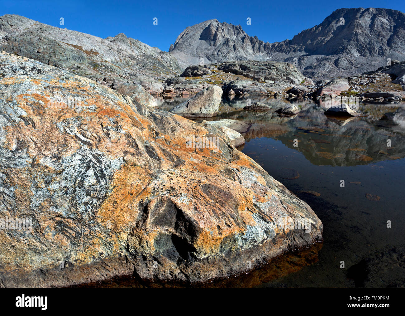 WYOMING - rock coloré sur la rive du petit lac et une réflexion de Fremont Peak dans la région du bassin de la Wind River Range Banque D'Images