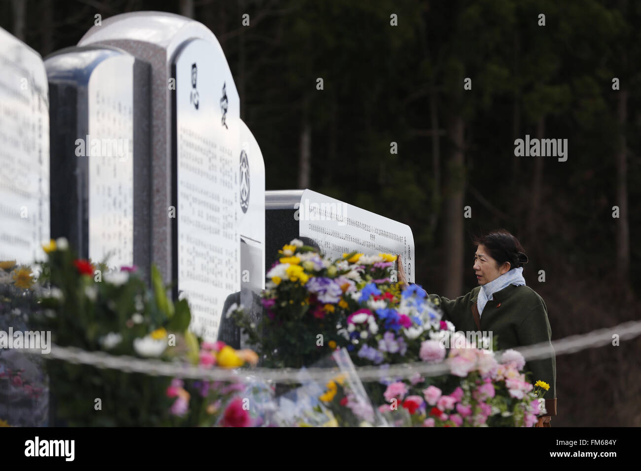 Une femme touche un culte à côté de l'école élémentaire Okawa sur le cinquième anniversaire du grand séisme de l'Est du Japon et de la catastrophe du Tsunami Ishinomaki le 11 mars 2016, Préfecture de Miyagi, au Japon. Exactement 5 ans plus tôt 74 des 108 étudiants de l'école ont perdu la vie à la suite du tsunami le 11 mars 2011. Il est prévu de reconstruire l'école, mais comme cela n'a pas encore été fixée. Le sort de l'a détruit des bâtiments devrait également être décidé plus tôt avec les résidents de la ville divisée quant à savoir s'ils devraient être conservés comme un mémorial ou supprimée. (Photo de Yusuke Nakanishi/AFLO) Banque D'Images