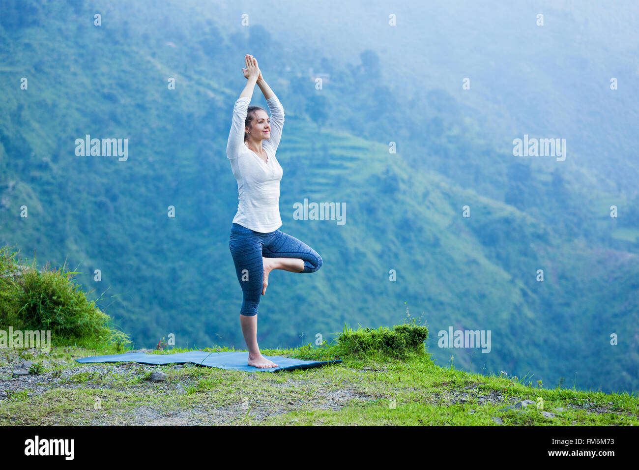 Woman in yoga asana Vrikshasana posture de l'arbre à l'extérieur Banque D'Images