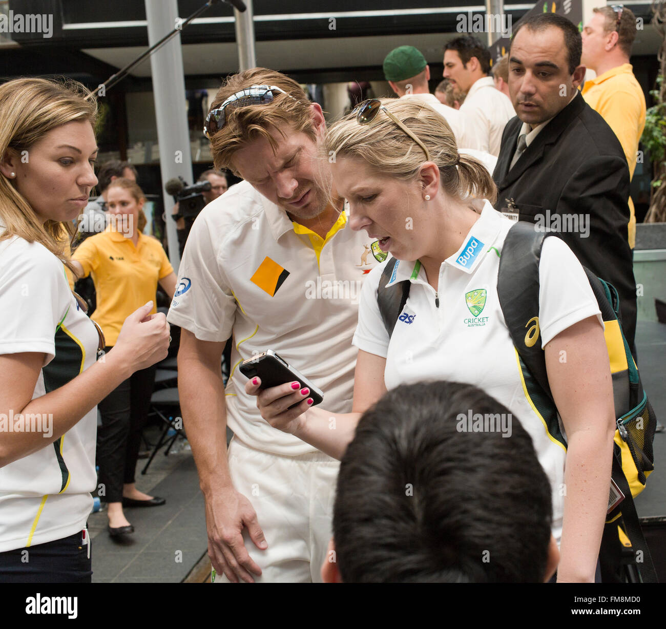 L'équipe australienne de cricket en Australie Brisbane avec les médias et supportrice looking at phone Banque D'Images