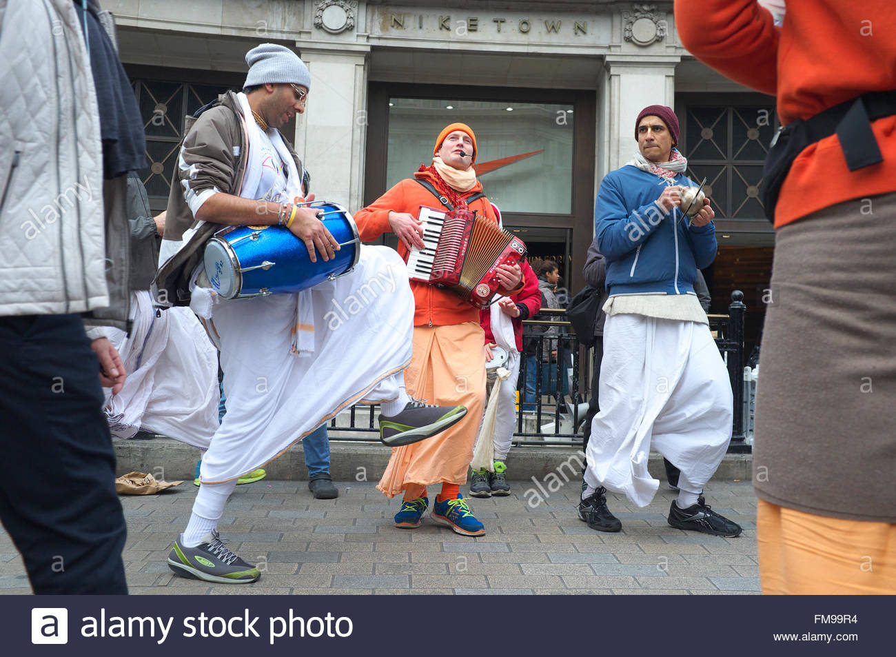 Membres de Hare Krishna danser et chanter parmi les piétons, passage sur Oxford Street au centre de Londres, au Royaume-Uni. Banque D'Images