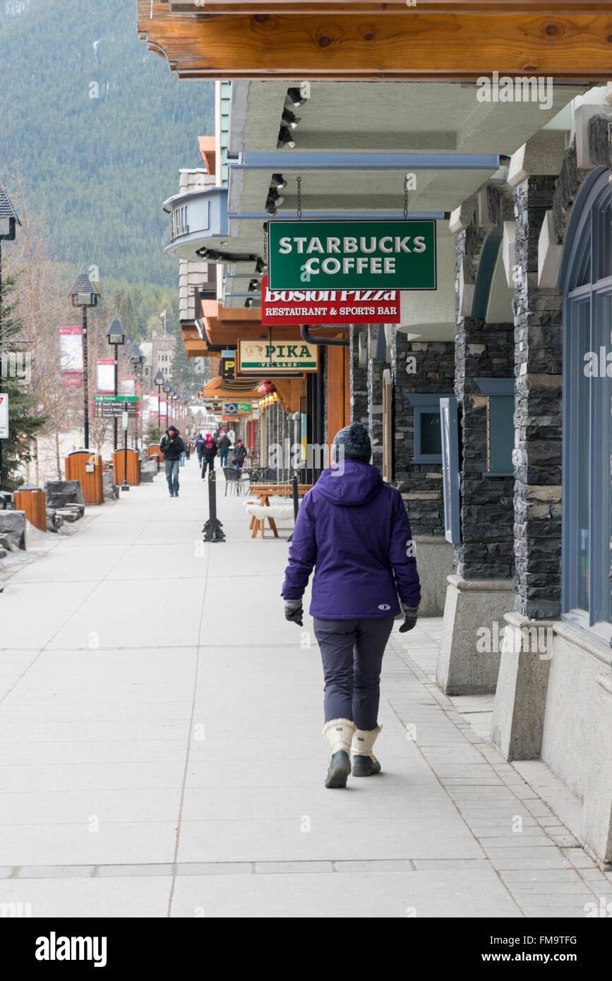 Un client marche dans l'Avenue Banff Banff Canada par Starbucks et de boutiques touristiques Banque D'Images
