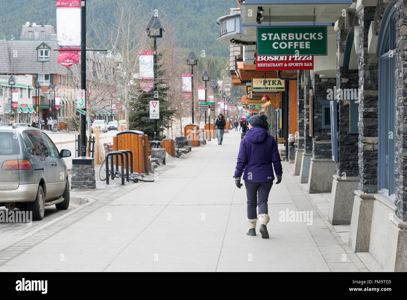 Un client marche dans l'Avenue Banff Banff Canada par Starbucks et de boutiques touristiques Banque D'Images