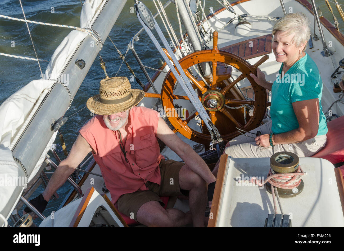 Une happy senior couple jouit d'temps ensemble de la voile sur un lac sur une belle journée d'été. Banque D'Images