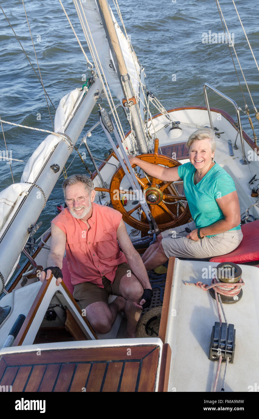 Portrait of a happy couple de retraités sur leur ketch classique comme ils naviguent dans la fin d'après-midi. Banque D'Images