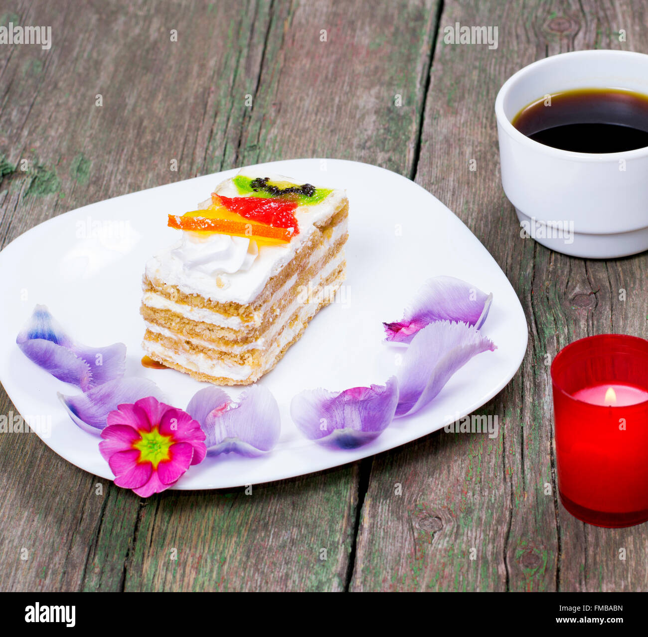 Gâteau sur une plaque une bougie et le café décoré de fleurs à proximité Banque D'Images
