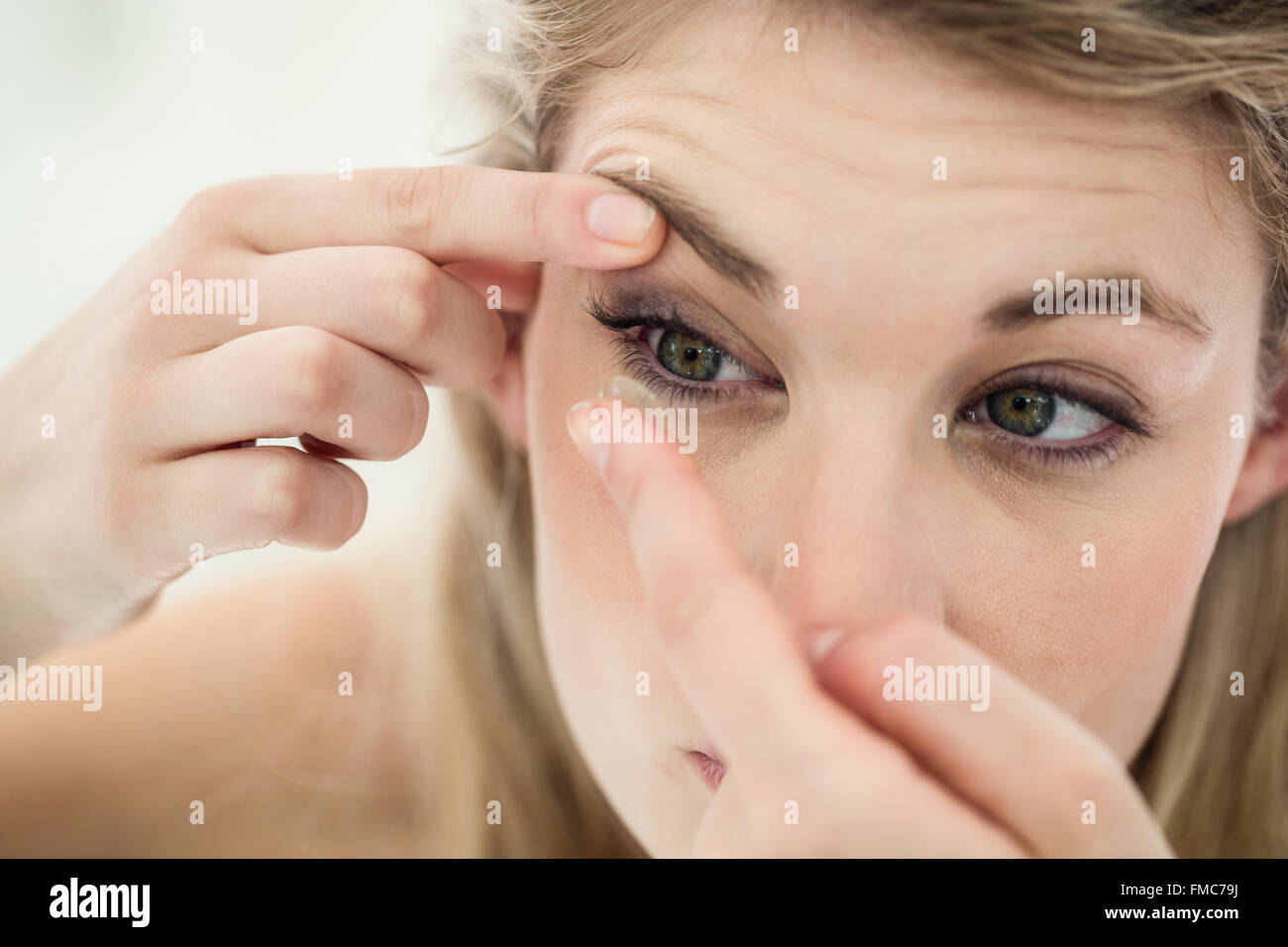Close-up of young woman applying contact lens Banque D'Images