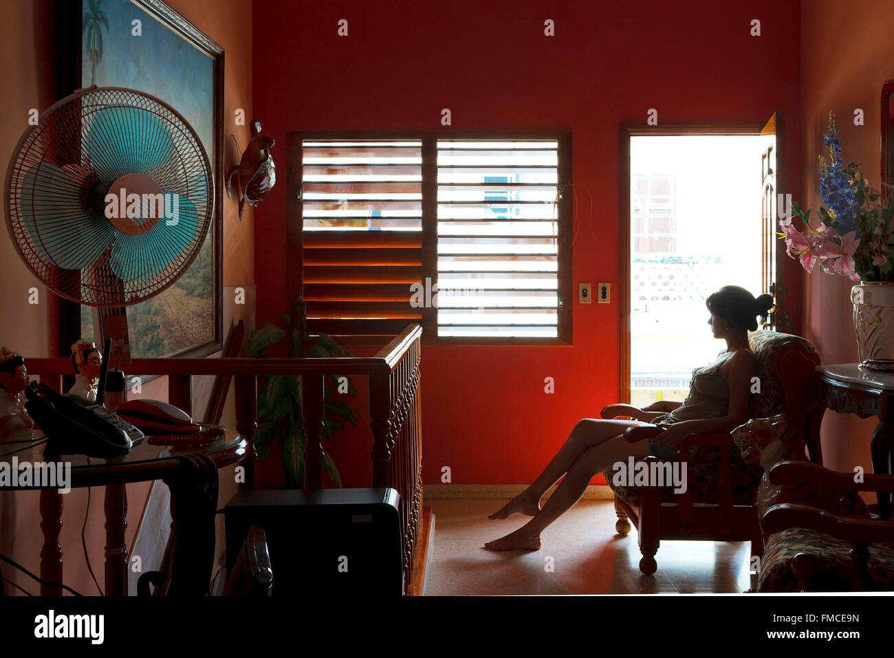 Cuba, La Havane, jeune femme assise sur une chaise confortable dans un appartement Banque D'Images