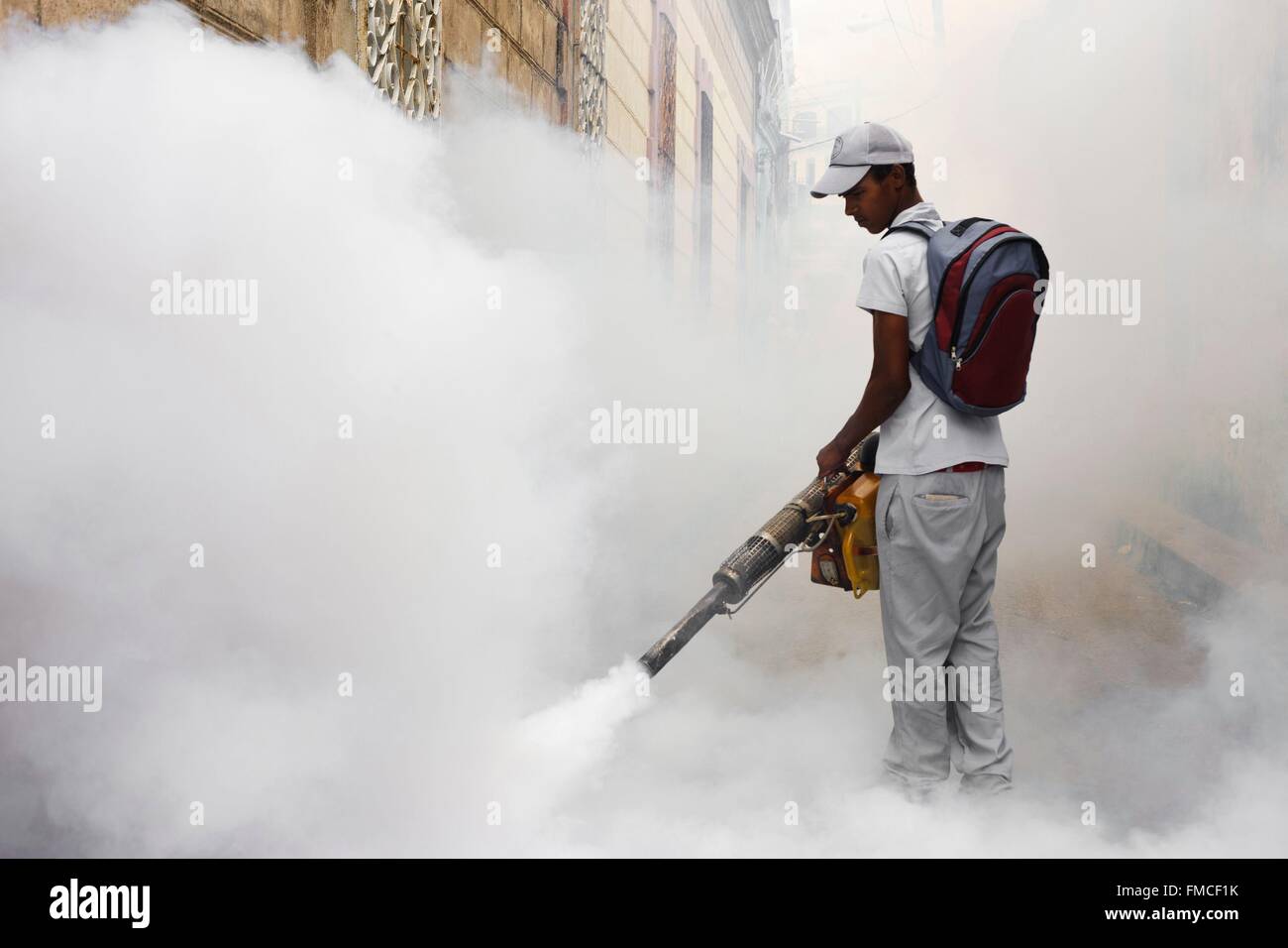 Cuba, Camaguey, Man spraying une fumée blanche dans la rue Banque D'Images Cuba, Camaguey, Man spraying une fumée blanche dans la rue Banque D'Images