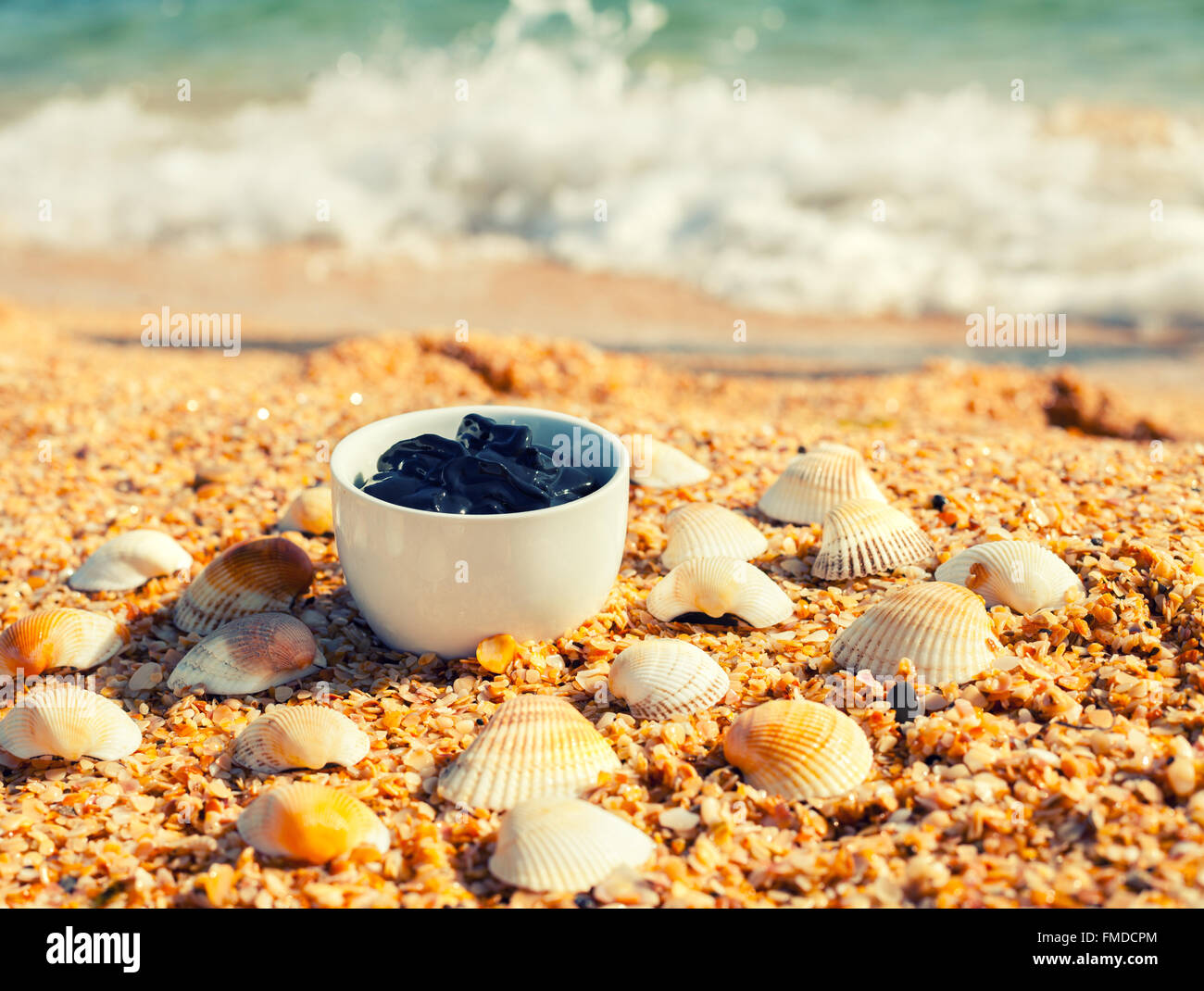 Boue de la mer morte pour les soins spa dans une tasse sur la plage Banque D'Images