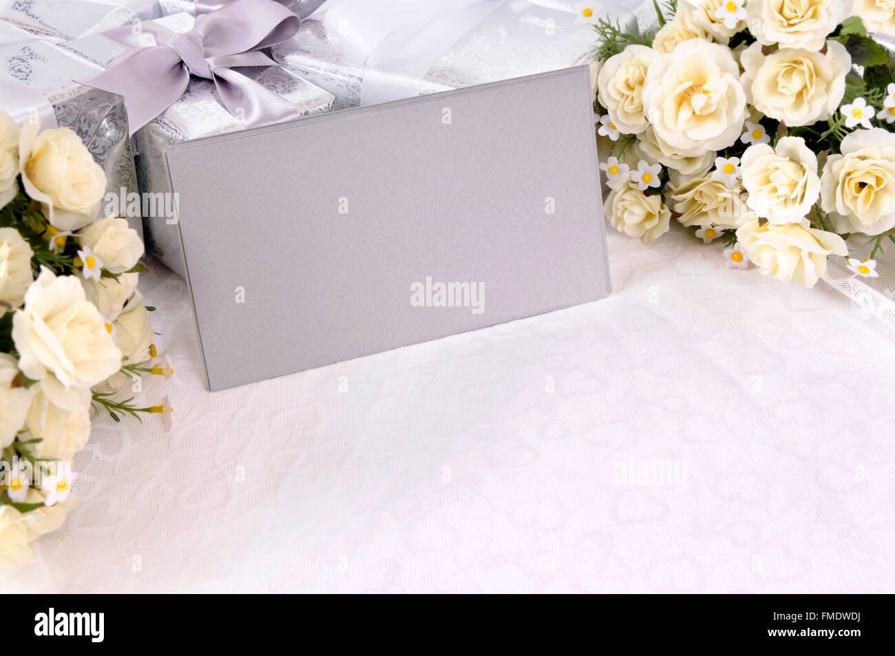 Enveloppes gris argent ou des invitations avec plusieurs cadeaux de mariage et de bouquets de roses blanches posées sur blanc dentelle mariée. Banque D'Images Enveloppes gris argent ou des invitations avec plusieurs cadeaux de mariage et de bouquets de roses blanches posées sur blanc dentelle mariée. Banque D'Images