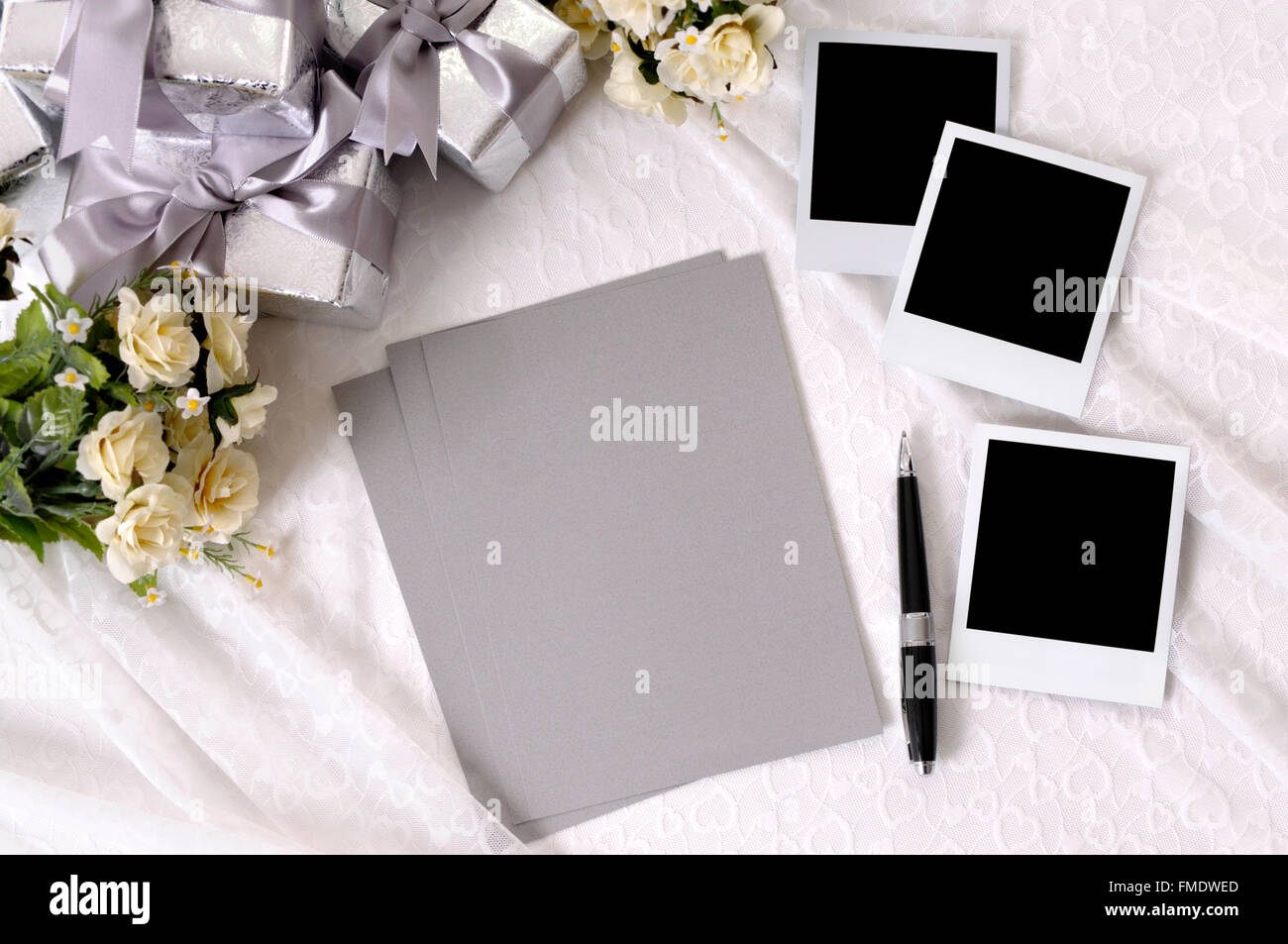 L'écriture papier et stylo blanc avec des impressions photo instantanée sur dentelle mariée avec plusieurs cadeaux de mariage d'argent Banque D'Images L'écriture papier et stylo blanc avec des impressions photo instantanée sur dentelle mariée avec plusieurs cadeaux de mariage d'argent Banque D'Images