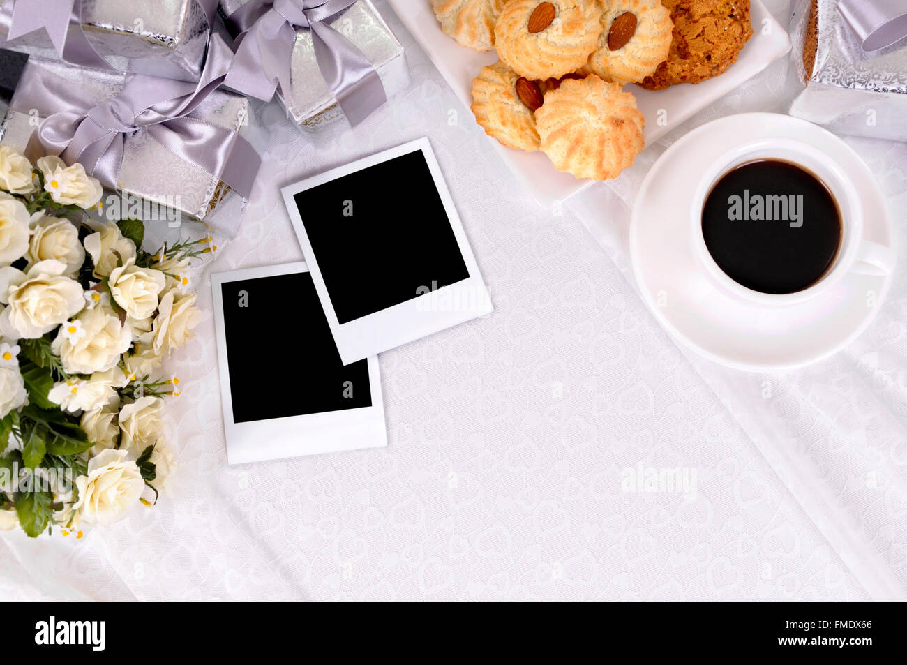 Cadeaux de mariage en blanc avec des impressions photo instantanée sur dentelle mariée avec plusieurs cadeaux de mariage d'argent et de roses blanches. Banque D'Images Cadeaux de mariage en blanc avec des impressions photo instantanée sur dentelle mariée avec plusieurs cadeaux de mariage d'argent et de roses blanches. Banque D'Images