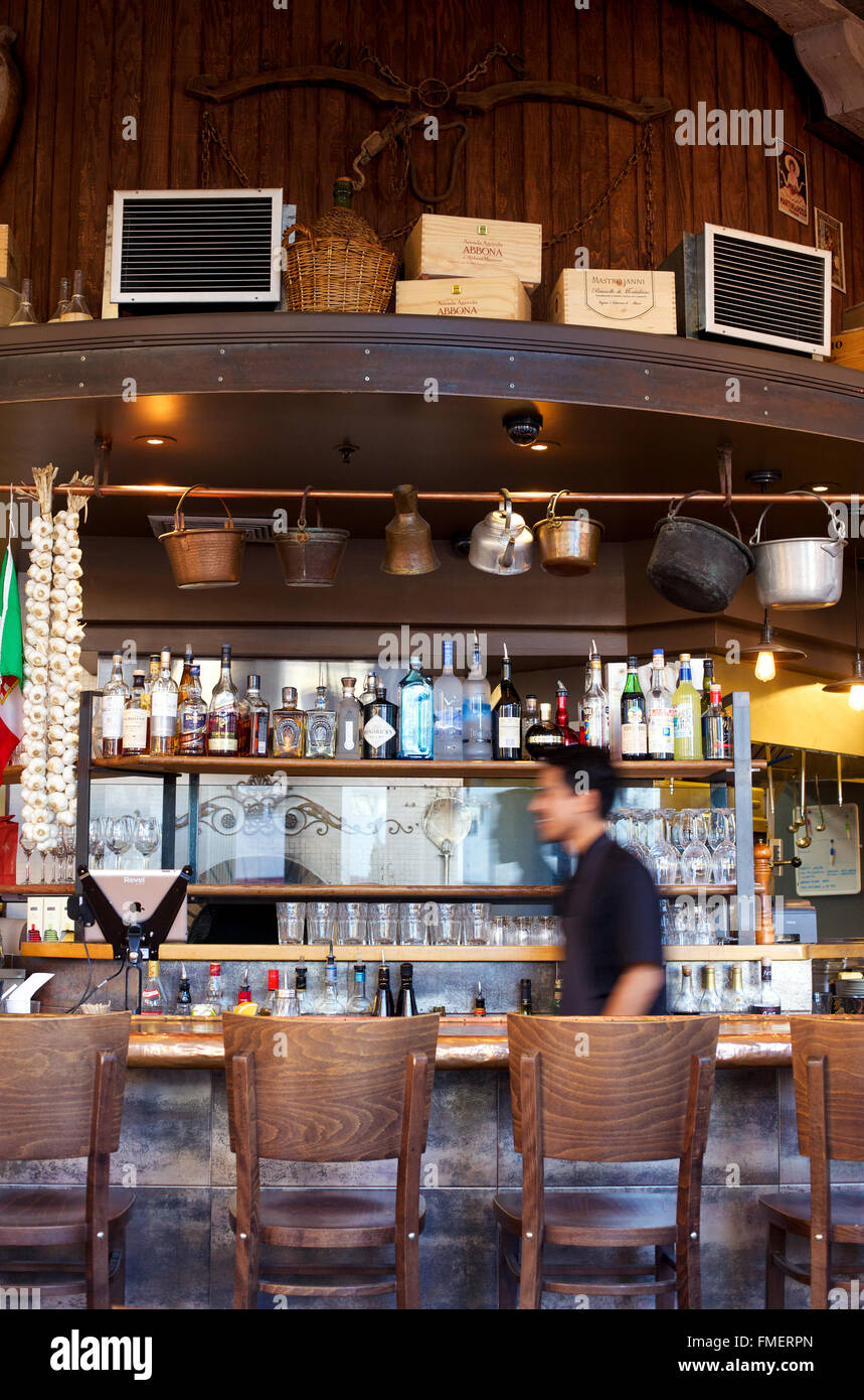 Un barman marche derrière un bar restaurant dans blurred motion. Banque D'Images