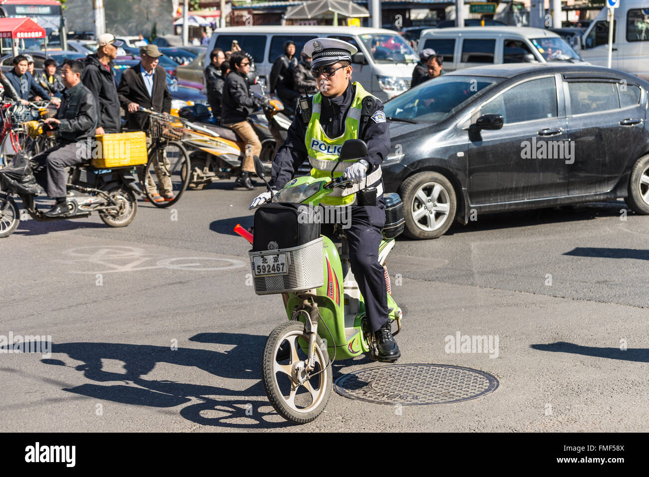 Policier chinois patrouille sur un scooter dans une rue animée de Beijing, Chine. Banque D'Images