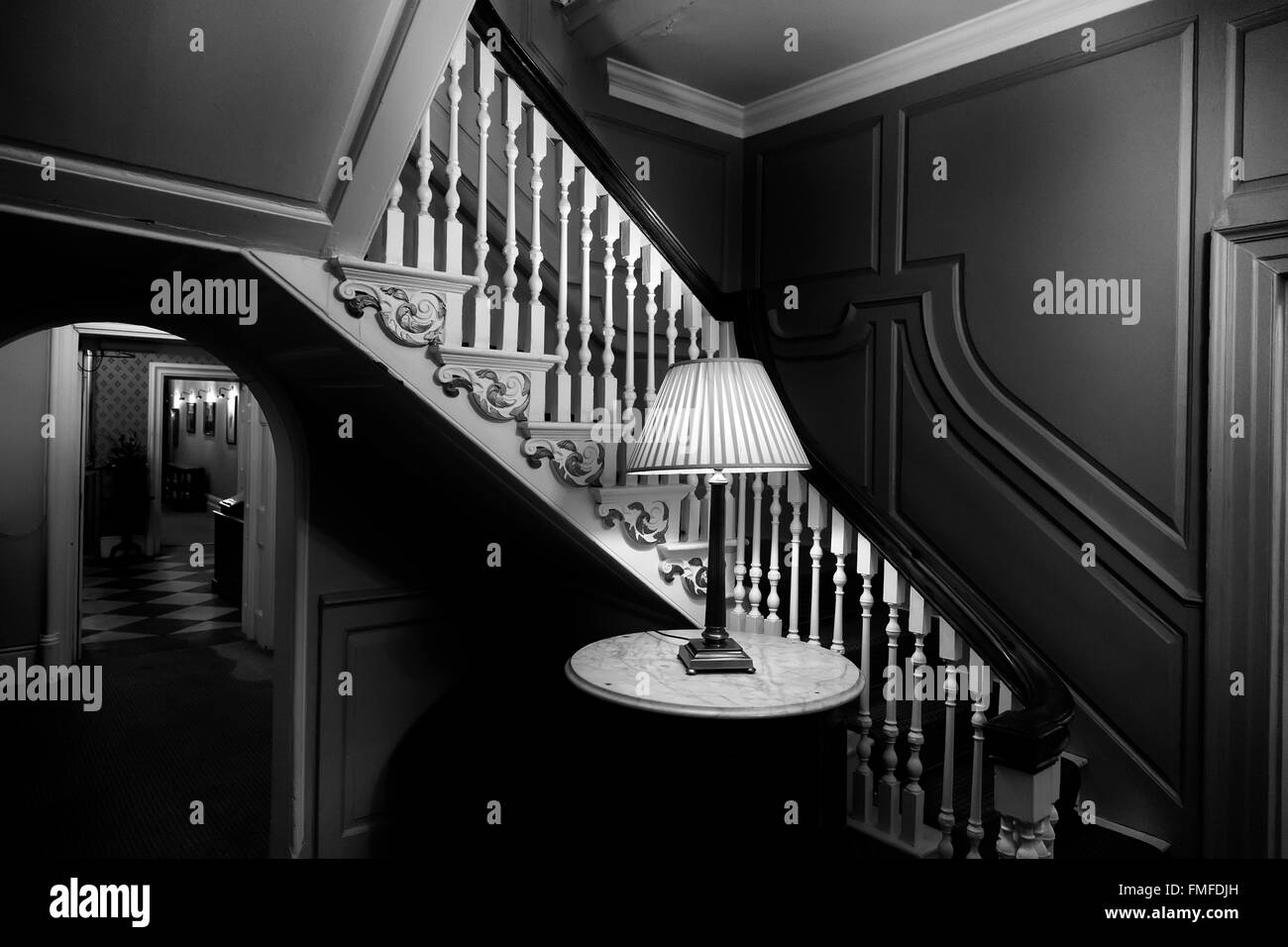 Palais de l'évêque britannique de l'intérieur montrant Lincoln hall et escaliers faiblement éclairé avec une lampe de table en noir et blanc Banque D'Images
