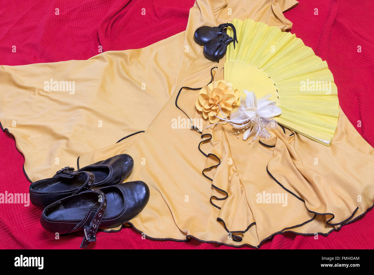 Vêtements jaune pour danse flamenco. Chaussures noires, le papier rose et des castagnettes sont posé sur une sous-couche rouge. Banque D'Images