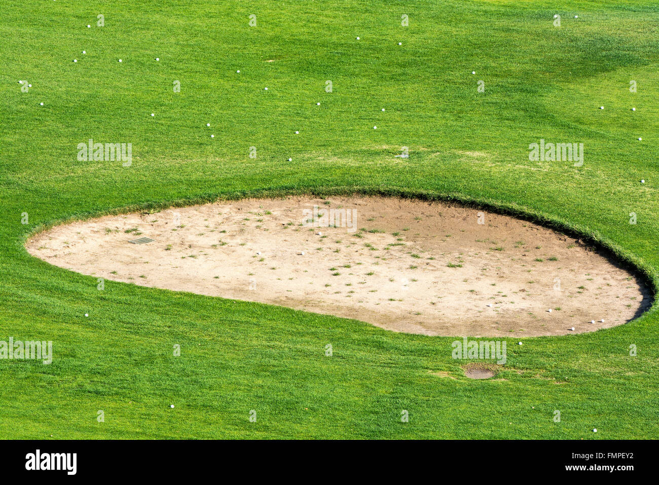 Gros plan d'une fosse de sable golf entouré par des balles de golf pendant un matin ensoleillé. Banque D'Images