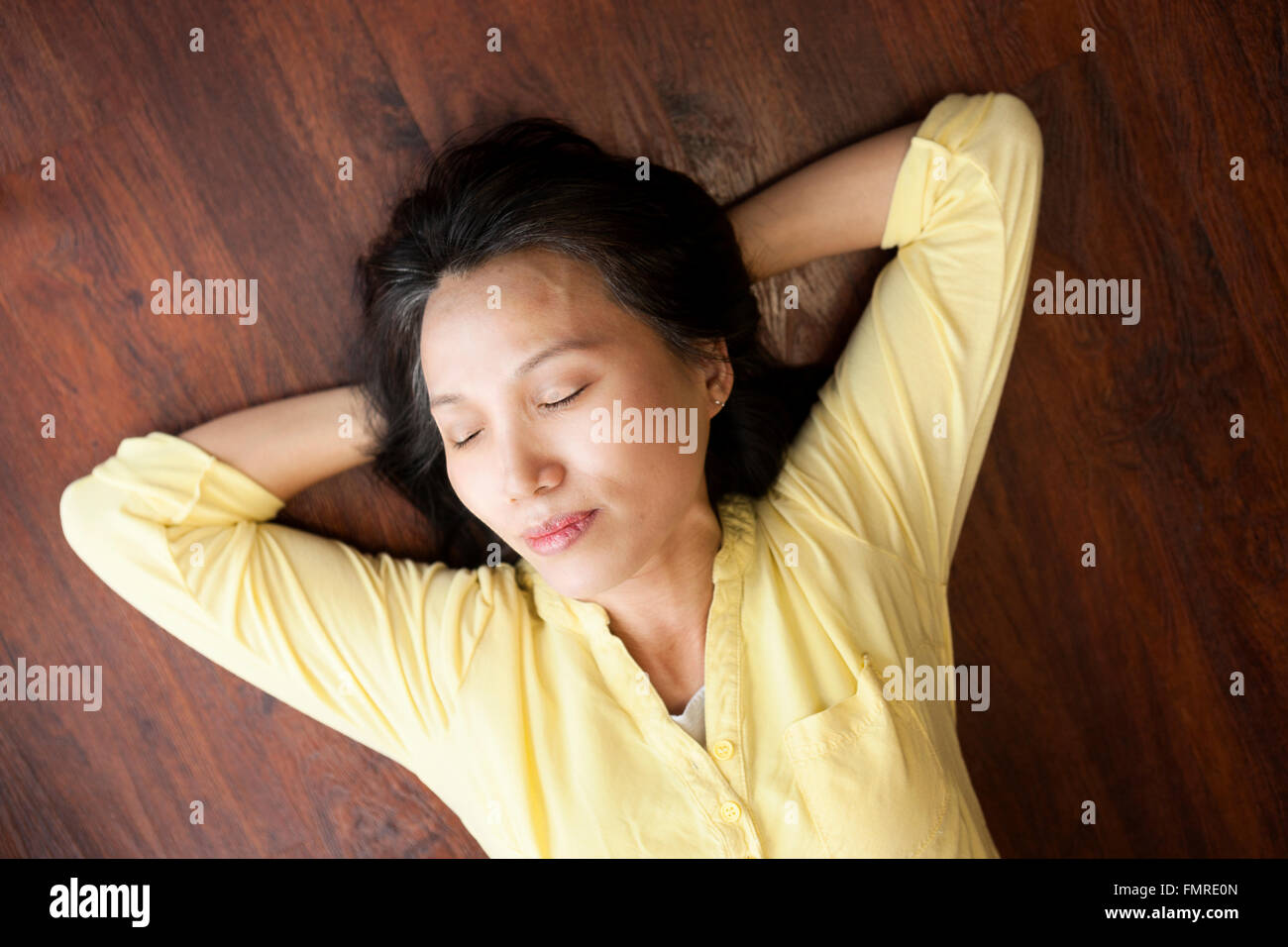 Une femme asiatique semble prendre une courte sieste sur le sol. Banque D'Images