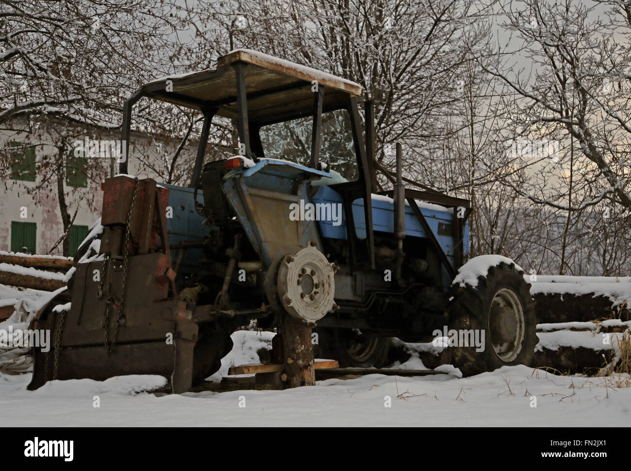 Tracteur abandonné sans une roue dans la neige en hiver Banque D'Images