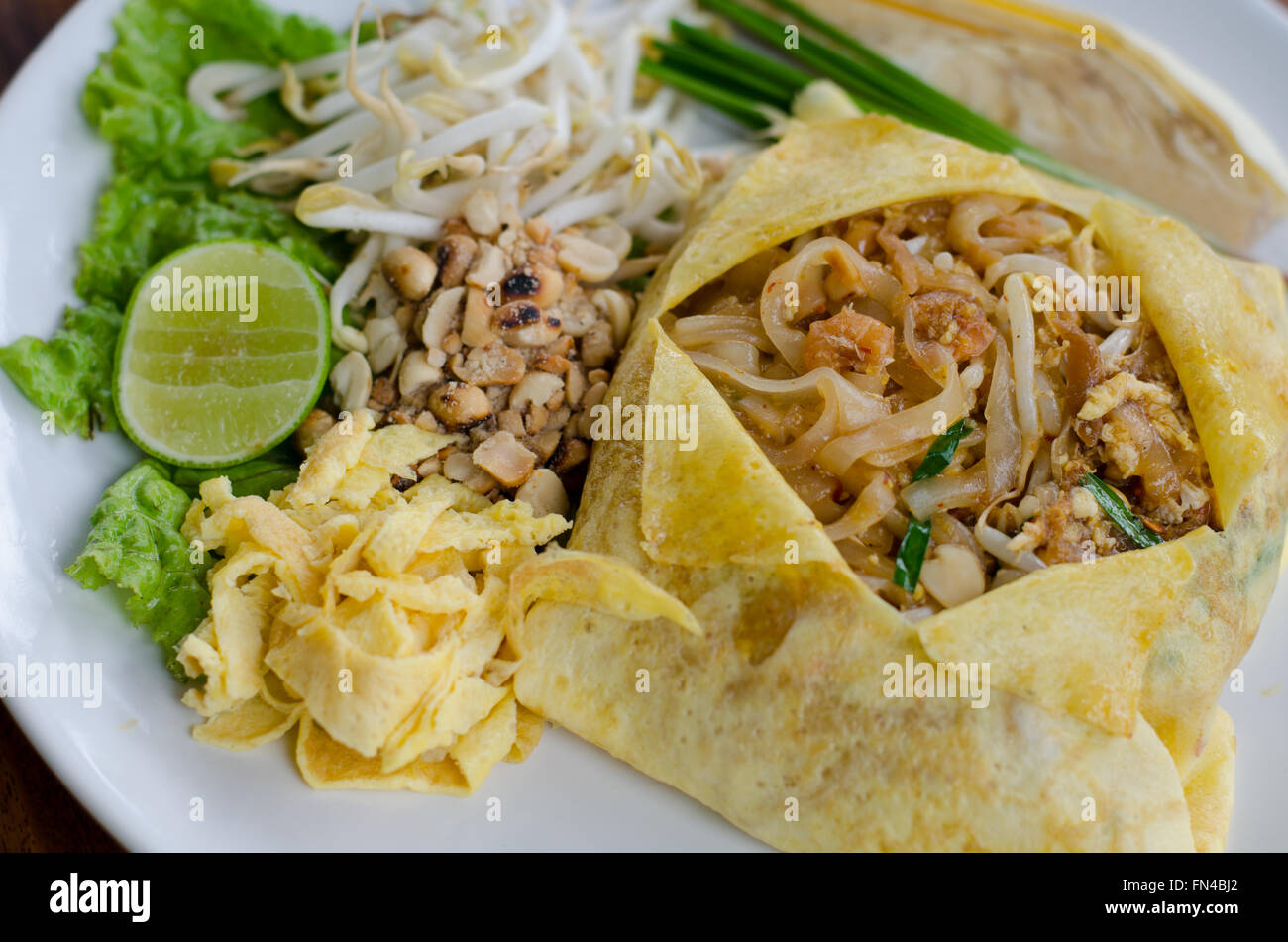 Thai Food Pad Thaï , nouilles sauté de porc aux oeufs. Du travail sur plaque blanche décorée avec différents assaisonnements. Banque D'Images
