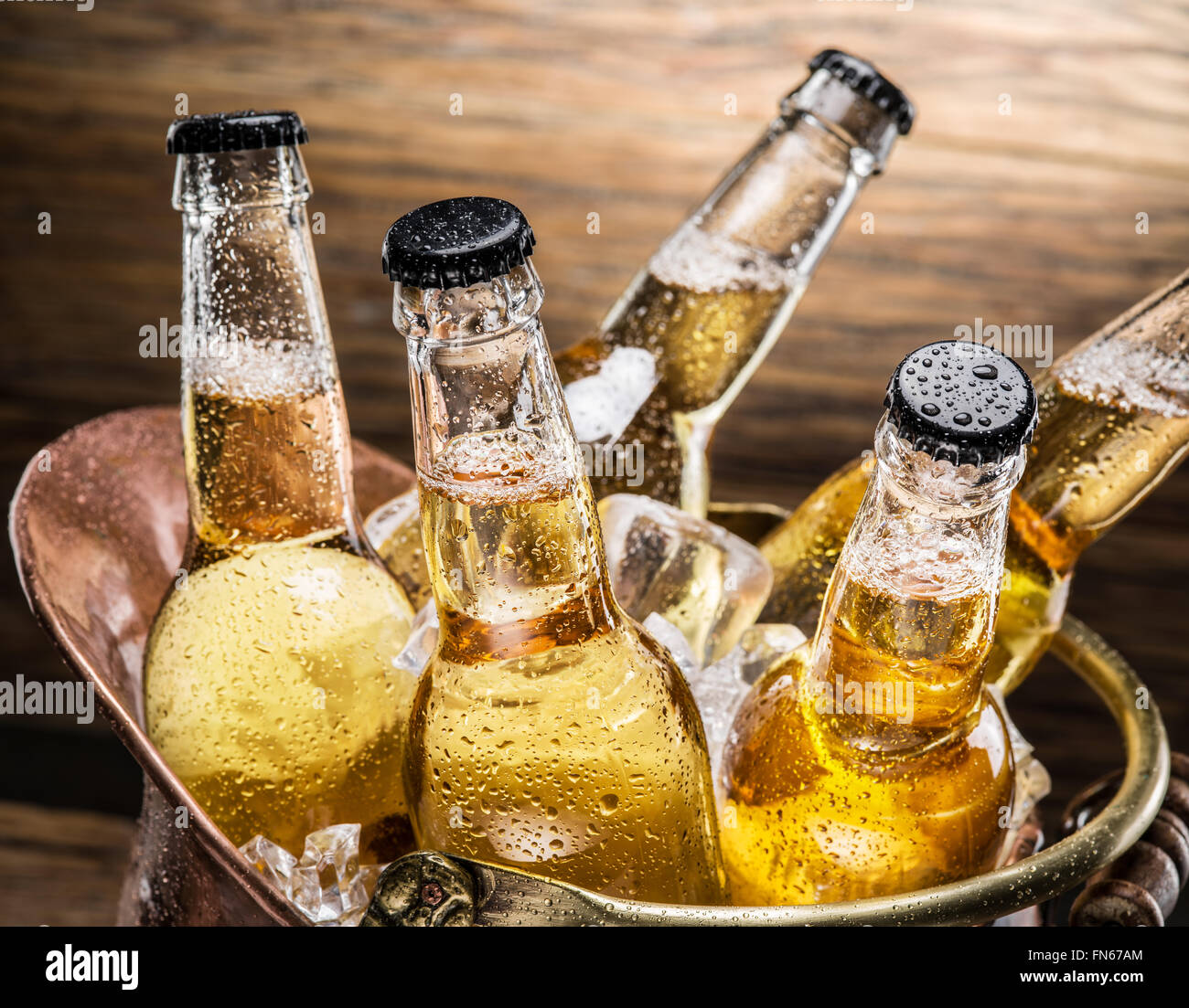 Bouteilles de bière froide dans le godet d'airain sur la table en bois. Banque D'Images