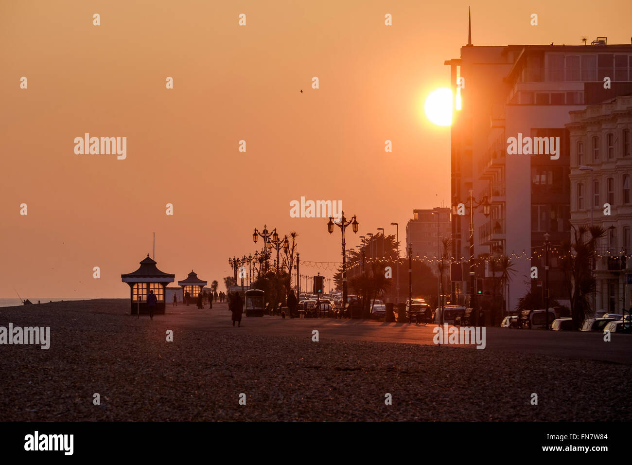 Le coucher du soleil le 13/03/2016 à Worthing, bord de mer. Photo : Le soleil se couche sur un front de vider lentement, l'éclairage la promade et refuges d'art-déco. Photo par Julie Edwards. Banque D'Images