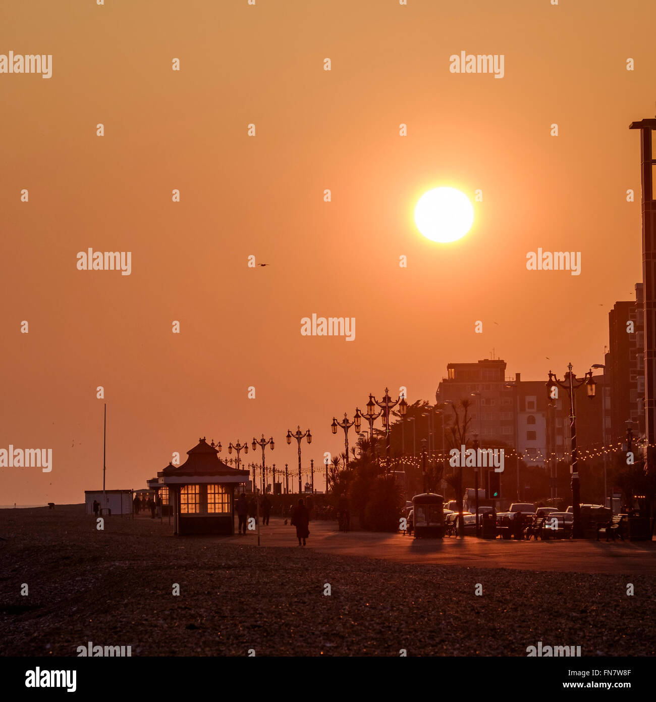 Le coucher du soleil le 13/03/2016 à Worthing, bord de mer. Photo : Le soleil se couche sur un front de vider lentement, l'éclairage la promade et refuges d'art-déco. Photo par Julie Edwards. Banque D'Images