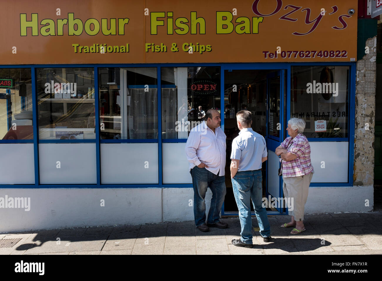 Trois personnes (deux hommes et une femme) parle en dehors d'un fish and chips shop, Ramsgate, Kent, UK Banque D'Images